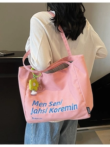 Pink canvas tote bag with blue embroidery and sunflower charm shown on a model