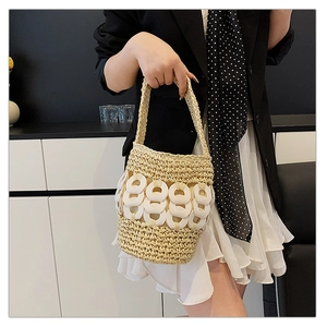 Detail of hand-woven straw bucket bag featuring modern acrylic chain links and soft texture