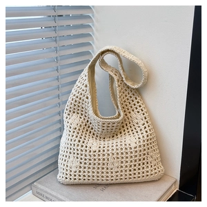 Detailed close-up of cream woven bucket bag with geometric hollow patterns on books