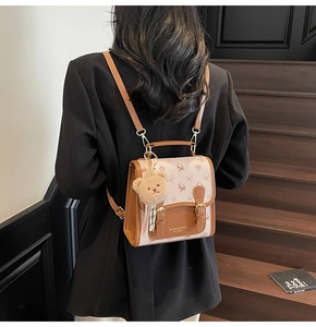 Detail eines Trend-Mini-Rucksacks mit Bärenanhänger und Hirschmuster auf Holztreppe