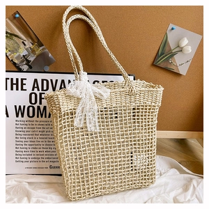 Vista dettagliata della borsa tote beige intrecciata con fiocco in pizzo e motivo traforato