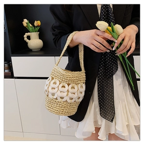 Detail of hand-woven straw bucket bag with decorative white rings and woven handle