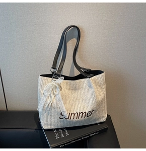 Detail of straw tote bag featuring Summer embroidery and a lace pearl bow charm