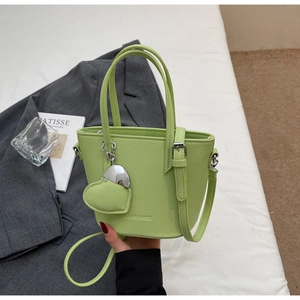 Detail of fruit green bucket bag with lychee texture and heart metal charm ornament