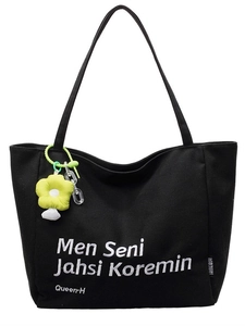 Minimalist black canvas tote bag with white embroidery and a yellow flower charm