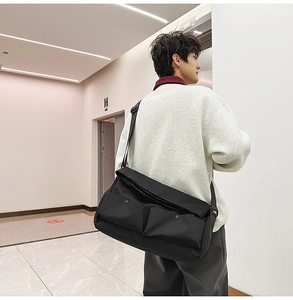 Vue détaillée d'un grand sac messager noir avec deux poches sur un mannequin homme