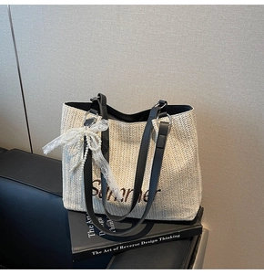 Detail of straw tote bag with Summer embroidery, lace bow, and leather straps on a book
