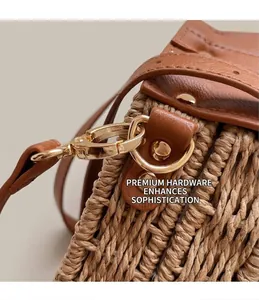 Detailed close-up of golden metal hooks and brown leather trim on a woven straw handbag