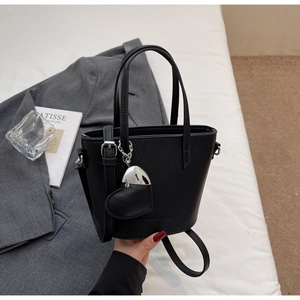 Detail of black pebbled leather bucket bag with silver heart charm and round handles