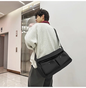 Détail d'un sac bandoulière noir avec deux poches à boucles et une sangle réglable