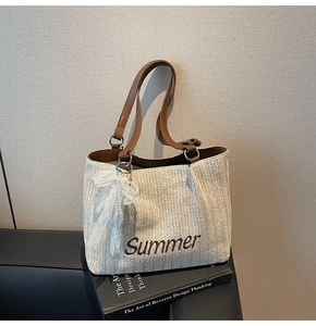 Detail of straw woven tote bag with Summer embroidery and lace bow on art book