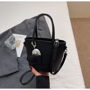 Close-up of black litchi pattern bucket bag featuring a heart charm and silver hardware