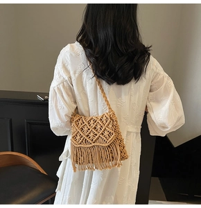 Détail d'un sac à bandoulière en paille tressée kaki avec de longues franges sur un modèle