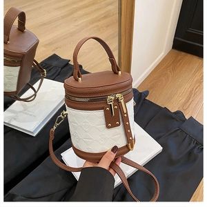 Detail of color-block bucket bag with embossed texture and brown lychee leather finish