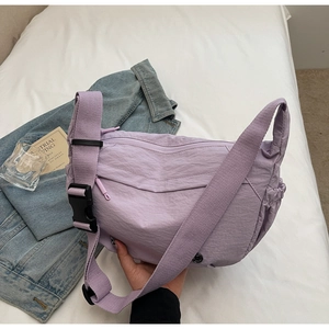 Detail of light purple nylon crescent crossbody bag with side drawstring pocket and wide strap
