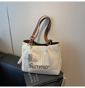 Detail of Summer straw tote bag with brown leather straps and pearl lace pendant charm