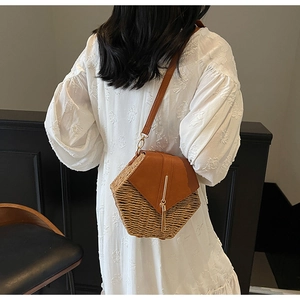 Detail of a hexagonal straw beach bag with brown leather flap and golden metal clasp