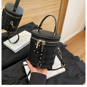 Detail of black cylinder bucket bag featuring lychee grain leather and checkered texture