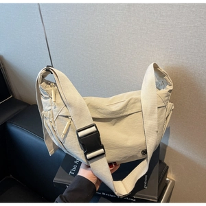 Detail of beige nylon crossbody bag featuring adjustable strap and buckle closure
