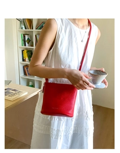 Sac seau en cuir rouge chic porté avec une robe blanche dans un cadre intérieur élégant