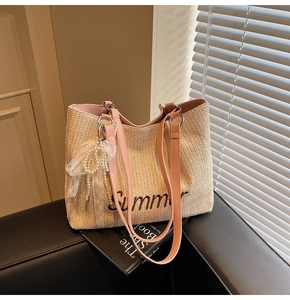Detail of straw tote bag with Summer embroidery, pink leather handles and pearl bow charm
