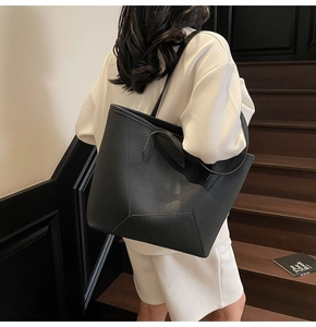 Detail of black pebbled leather tote bag featuring unique geometric stitching at the bottom