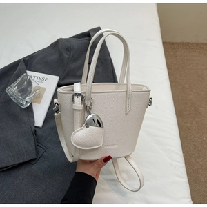 Detail shot of beige lychee texture leather bucket bag with silver heart pendant