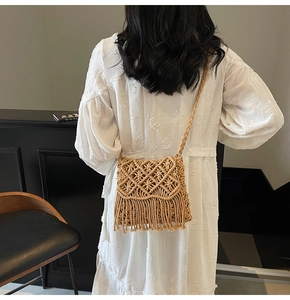 Detail of bohemian hand-woven straw bag with fringe tassels and braided shoulder strap