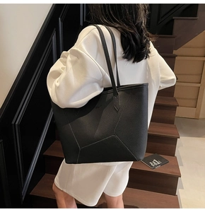 Close-up of black leather tote bag featuring geometric stitching and twin shoulder straps