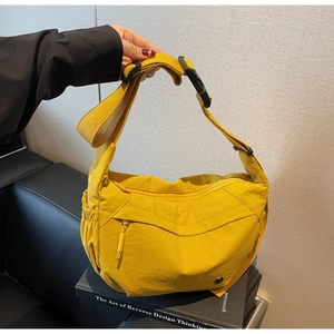 Close-up of bright yellow nylon crossbody bag with zipper details and wide strap
