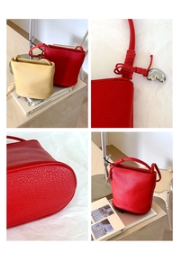 Détails d'un sac seau en cuir grainé montrant les finitions rouge et beige et le pendentif