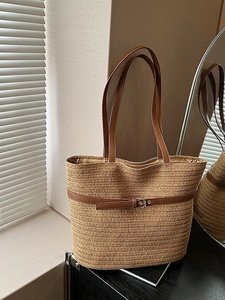 Large straw tote bag with brown leather straps and metal buckle for beach vacations
