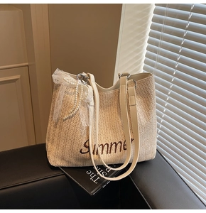 Detail of straw tote bag with Summer embroidery, white lace bow, and pearl charm