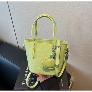 Close-up of neon green leather bucket bag featuring lychee texture and heart charm