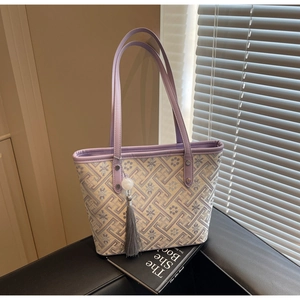 Dettaglio di ricamo floreale su borsa tote con nappa viola e finiture in ecopelle