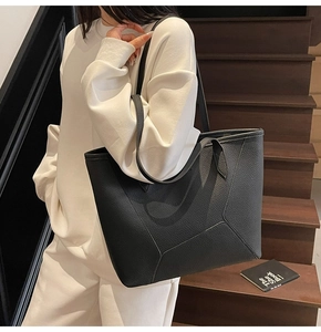 Detail of a large black tote bag with lychee grain texture and geometric stitching details
