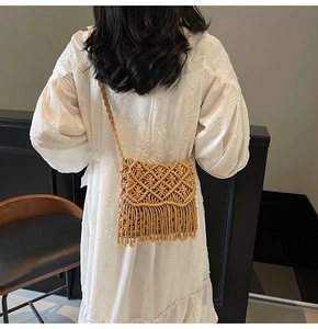 Détail d'un sac bandoulière en paille avec tissage en losange et franges sur modèle