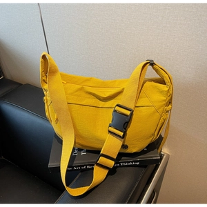 Detailed macro view of yellow nylon crescent bag texture and wide adjustable strap