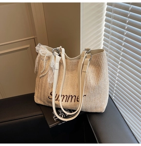 Detail of straw tote bag featuring Summer embroidery, lace bow, and pearl charm accents