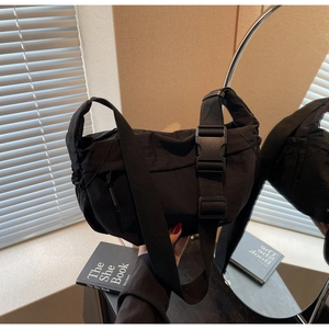 Close-up of black crossbody bag with industrial buckle and smooth zipper detail