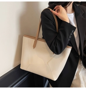 Detail of white and brown leather tote bag with pebble texture and slim shoulder straps