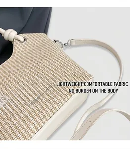 Vue détaillée d'un sac seau en paille tissée avec bordure en cuir crème et métal