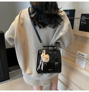 Détail d'un sac noir avec motif cerf et pendentif ours porté par un mannequin