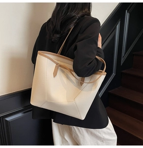 Detail view of large cream tote bag with brown straps worn over shoulder on a model