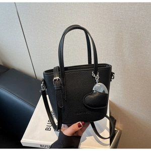Detail of black lychee grain leather bucket bag with silver heart charm and metal hardware
