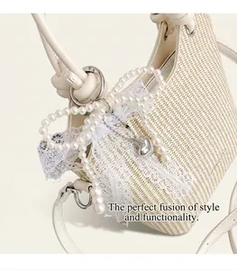 Détail du sac seau en paille avec nœud en perles, dentelle et pendentif cœur argenté