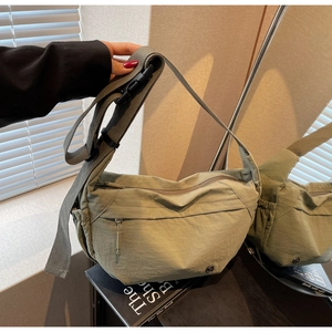 Detail of pea green nylon crescent shoulder bag with adjustable strap and front zip pocket