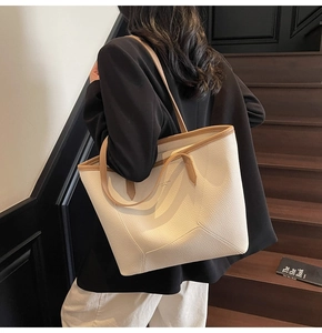 Detail of minimalist cream leather tote bag with camel contrast handles and V-shaped stitching