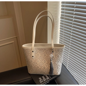 Dettaglio ravvicinato di una borsa tote crema con motivi geometrici e nappa decorativa