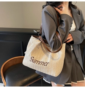 Close-up of woven straw tote bag with Summer embroidery and brown leather strap